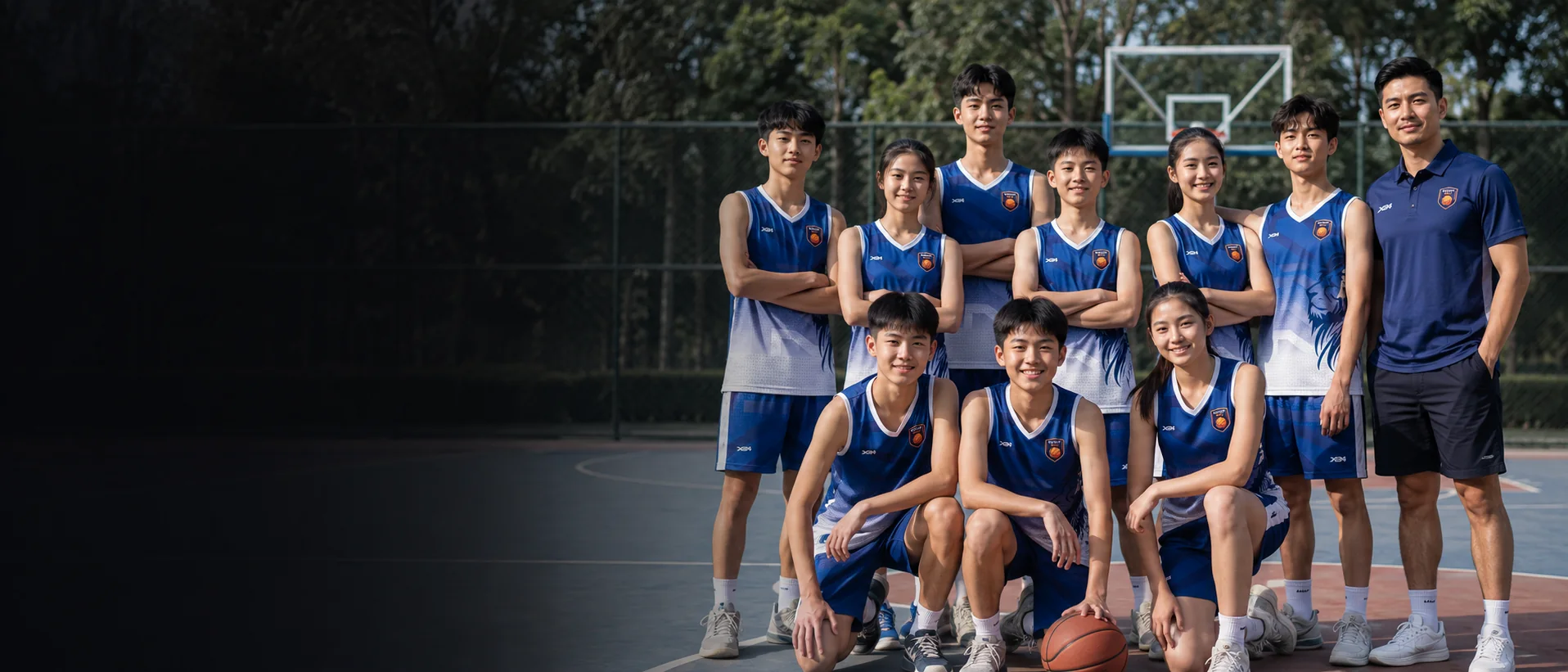 Đội bóng rổ học sinh mặc đồng phục xanh thi đấu trên sân ngoài trời cùng huấn luyện viên